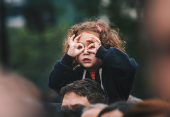 child sitting on father's shoulders in a crowd