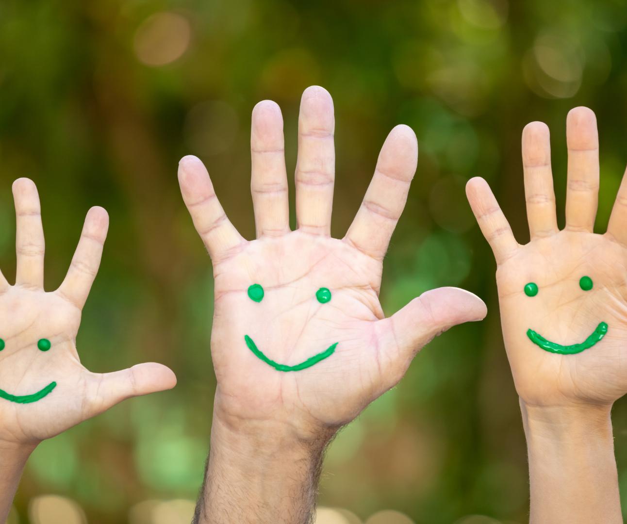 3 hands raised with a green smiley drawn on it