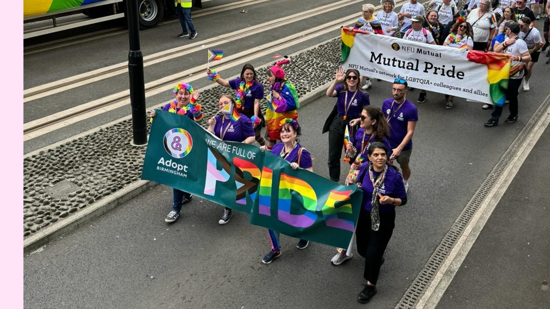 Group of people walking and smiling as a group in a parade with a large banner
